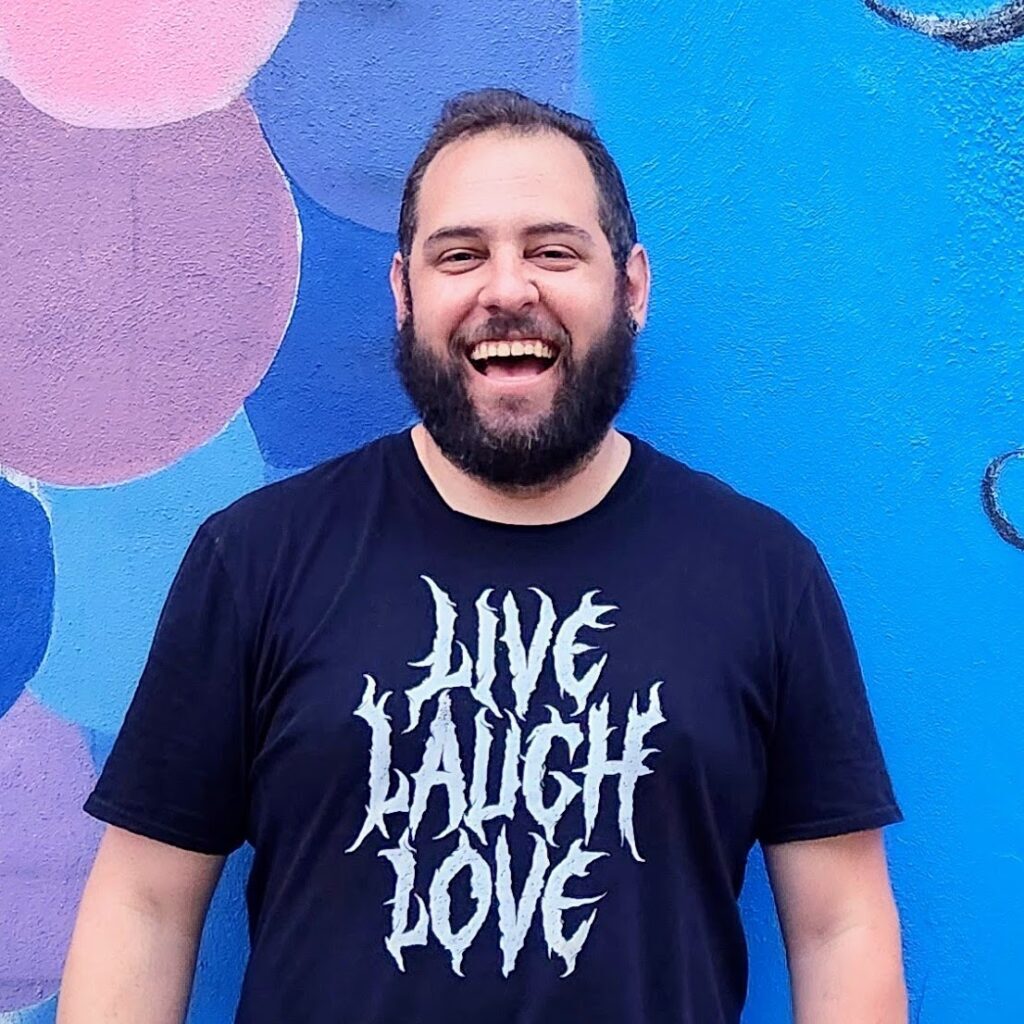 Nick Norton laughing in front of a blue wall